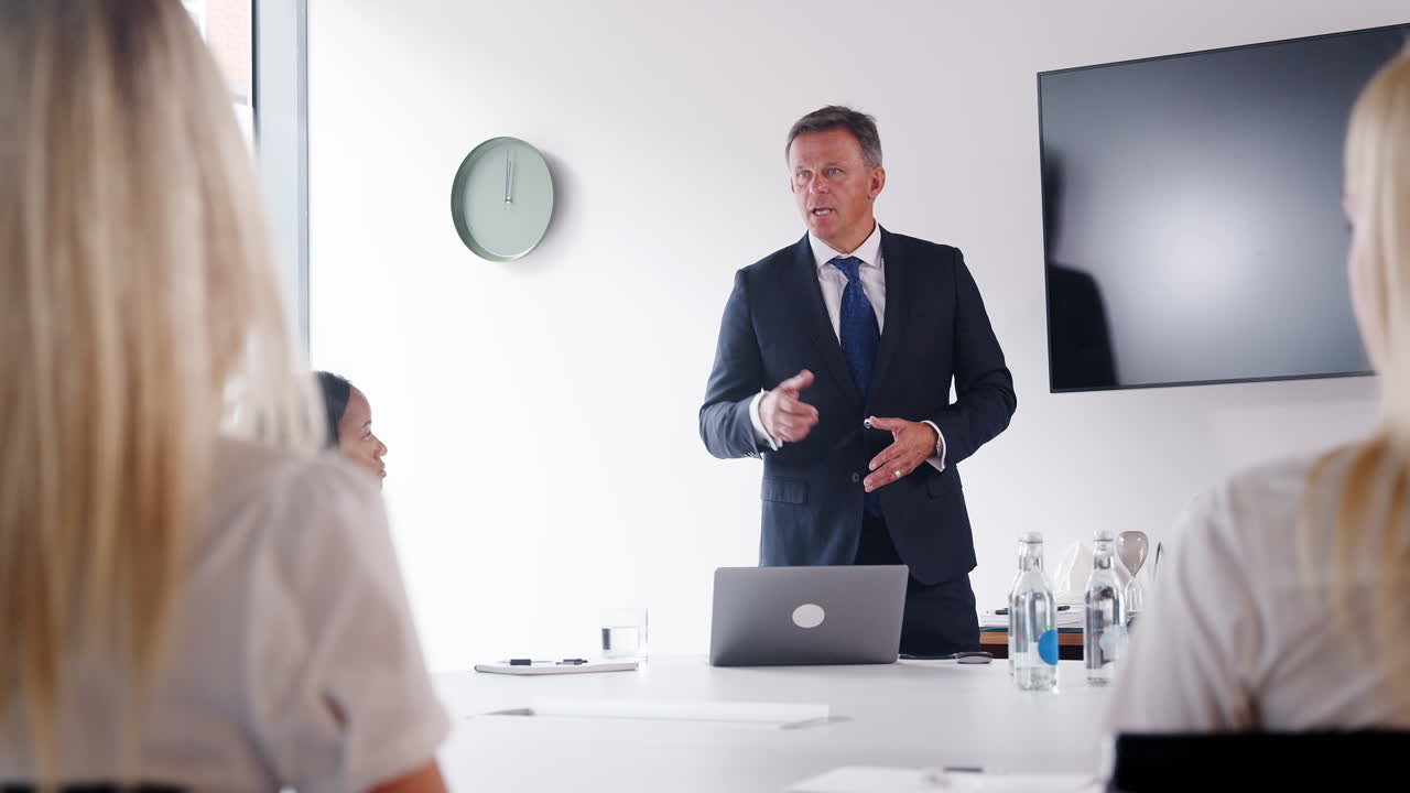 hombre de negocios maduro dirigiéndose a una reunión de grupo en torno a la mesa en el día de evaluación de reclutamiento de graduados