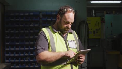 trabajador de fábrica masculino caucásico en una fábrica con un chaleco de alta visibilidad trabajando