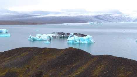 scenic aerial view of a iceberg in a glacier lake in iceland, surrounded by snowy mountains