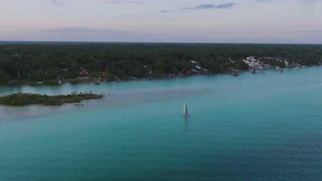 sailboat sailing on beautiful bacalar, mexico coast at sunset - aerial