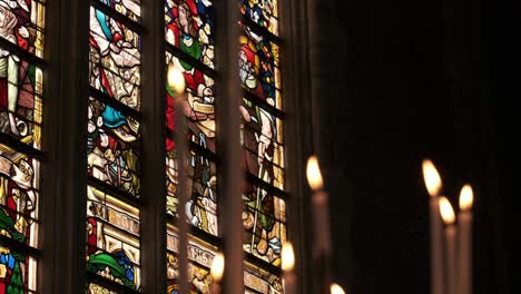 Colorful-stained-glass-windows-with-lit-candles-in-a-church