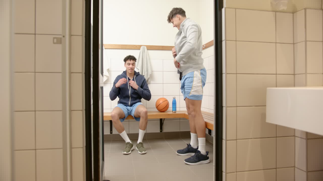 Basketball players changing in locker room, preparing for game with focus