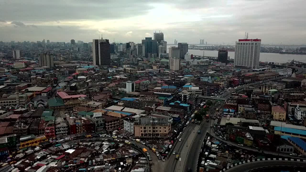 Letecký pohled na Lagos Island, Nigérie, ukazující husté městské střechy, rušné silnice a panoráma výškových budov poblíž laguny Lagos pod zataženou oblohou – panorama západoafrické megacity.