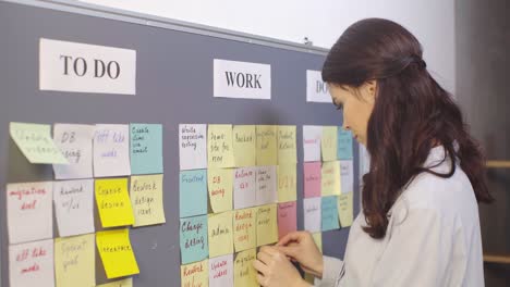 attractive scrum master putting sticky note with ui lettering on board