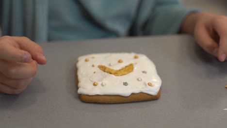 vista de cerca de las manos de los niños decorando galletas caseras para las vacaciones. un niño decora galletas presionando fondant o pasta de un tubo