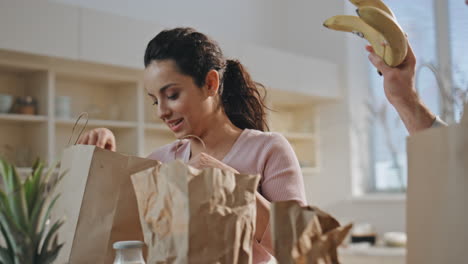 pareja bromeando productos cocina de cerca. cónyuges felices desempaquetando compras de alimentos