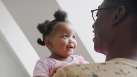 father playing game with baby daughter and lifting her in air in loft apartment