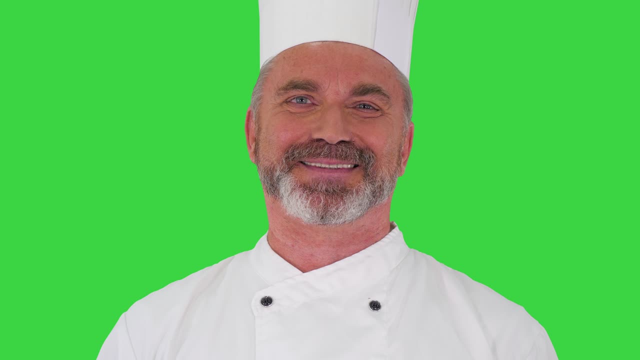 Elderly professional chef man showing delicious gesture to camera on a Green Screen, Chroma Key