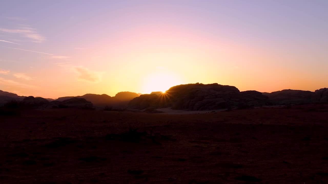 el sol se sumerge detrás del paisaje montañoso durante una hermosa puesta de sol con rayos de luz solar en el remoto desierto de wadi rum en jordania