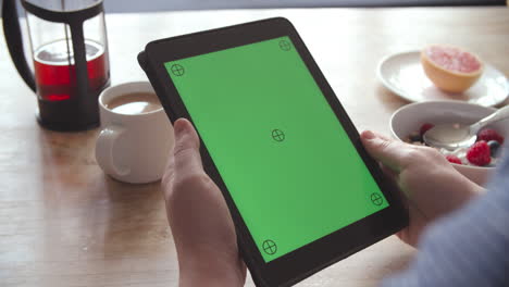 Hände-Halten-Digitales-Tablet-Mit-Grünem-Bildschirm-Beim-Frühstück