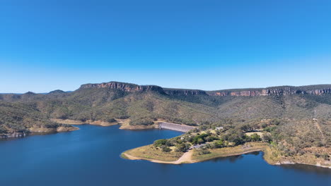 buen día de verano aéreo se acerca al promontorio con instalaciones turísticas que sobresalen en el profundo lago azul de cania