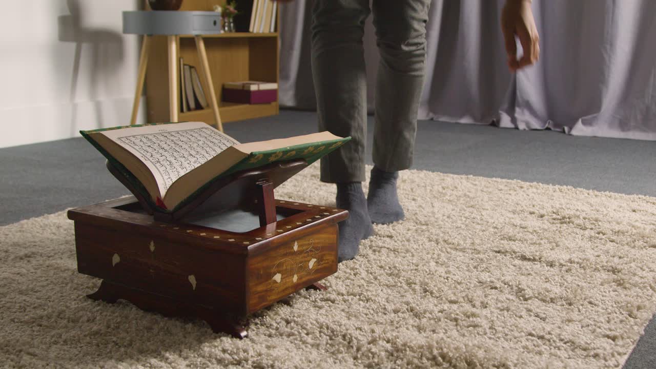 Close Up Of Muslim Man At Home Sitting On Floor And Reciting From The Quran