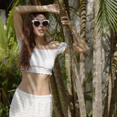 sensual woman standing near tropical plant on hot day