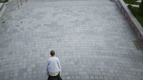 top view of the man with one leg on crutches training and doing tricks on the street.