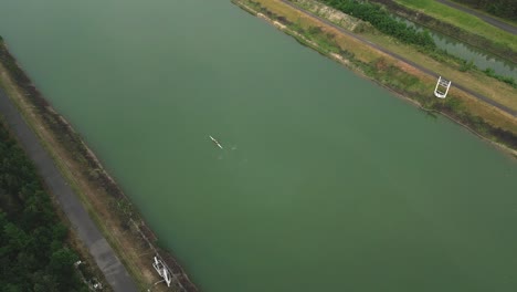 Eine-Luftaufnahme-Der-Natürlichen-Ruderarena-Mit-Einem-Doppelzweier,-Der-Auf-Dem-Ruhigen-Wasser-Reitet