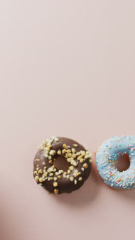 video de rosquillas con glaseado y una taza de café sobre un fondo rosa