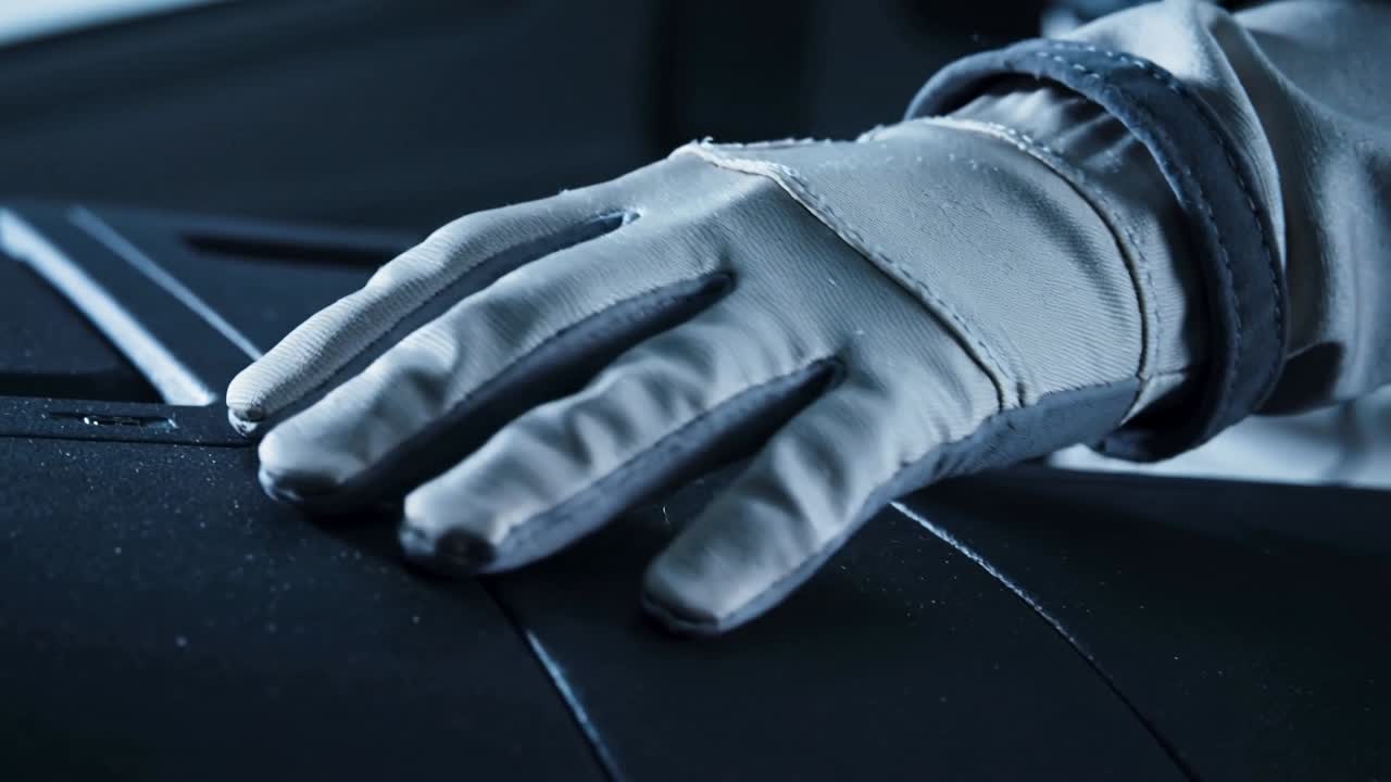 Main gantée traçant une couture sur le panneau du cockpit, sentant la poussière et inspectant la dragonne