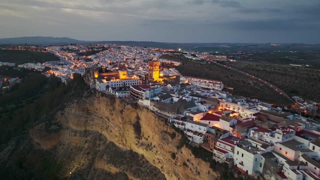 Gorgeous white town on the mountain - Arcos de la Frontera - after sunset with city lights.  Aerial evening view of Arcos de la Frontera, Andalusia, Spain