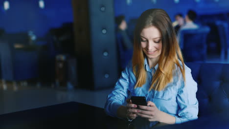 a young caucasian woman rests in a cafe uses a smartphone