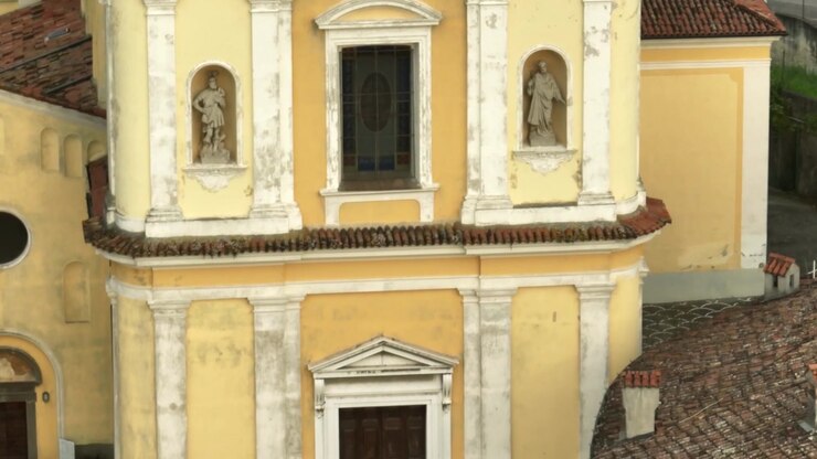 Vista aerea della facciata ornata e storica e del tetto in tegole della Chiesa di San Giorgio Martire sul Lago d'Iseo, Italia, circondata dal villaggio