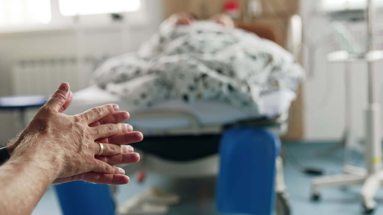 Man rubbing his hands nervously sitting in the hospital ward. Worrying husband supporting his pregnant wife.