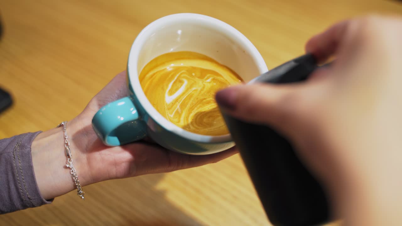 Female hands pouring milk. Professional barista pouring steamed milk into coffee cup