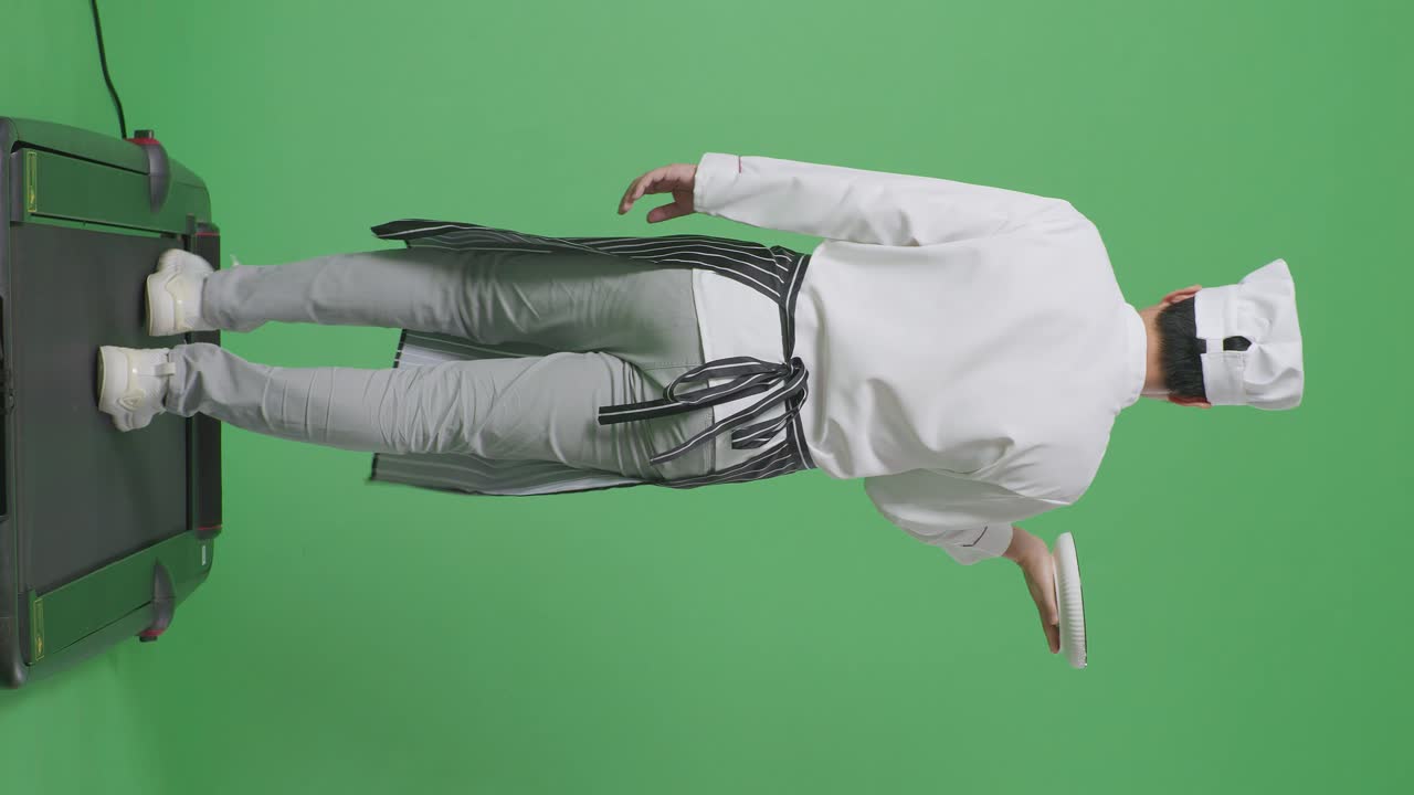 녹색 스크린 배경 스튜디오에서 트레드밀을 는 동안 접시를 들고 있는 아시아 남성 요리사