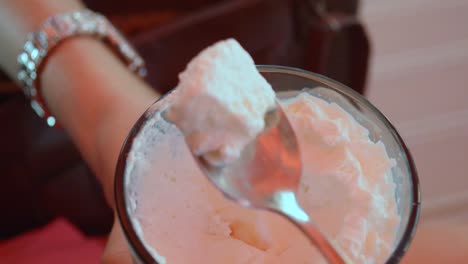 Girl-eating-whipped-cream-from-the-top-of-the-coffee-with-a-long-silver-spoon