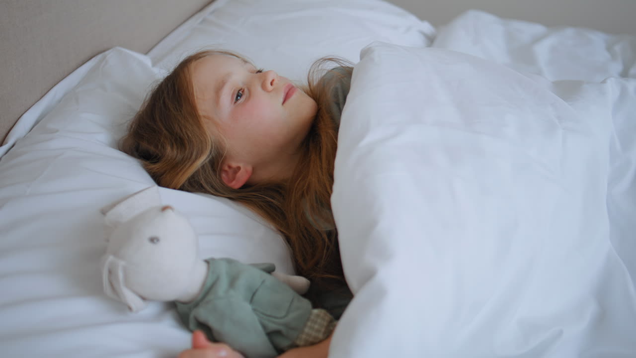 Little baby sleeping bed sweetly stretching wake up closeup. Girl embracing toy