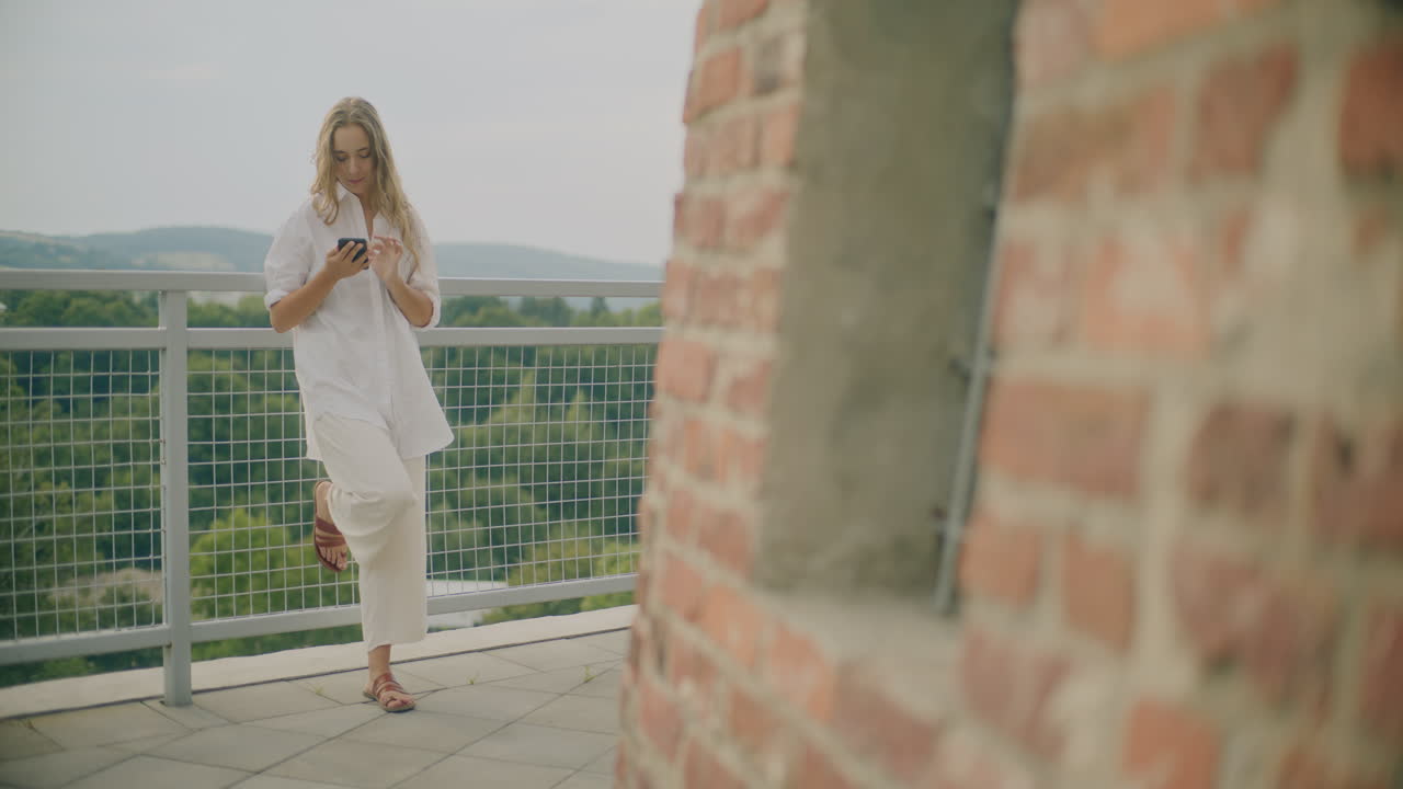 mujer escribiendo en un teléfono inteligente al aire libre