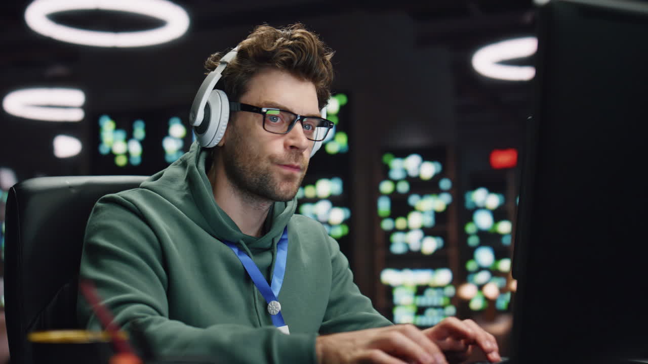 auriculares hombre codificando computadora en la sala del servidor primer plano. desarrollador escuchando música