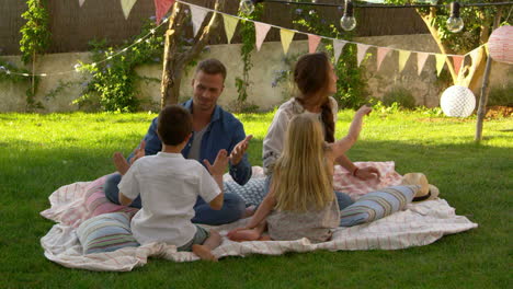 family relaxing on blanket in garden