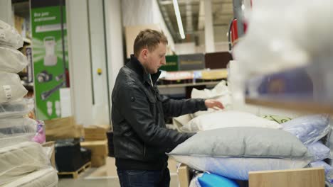 man chooses pillow in a shop. bed linen shop