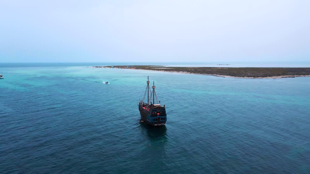 A majestic pirate ship glides across the serene, turquoise waters of a tropical paradise, surrounded by lush islands and clear skies.