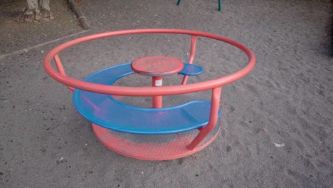 Red-and-blue-rusted-Carousel-spinning-around,-day-time