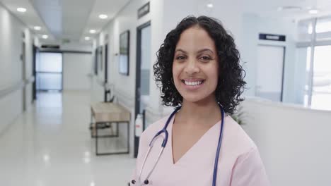 Portrait-of-happy-biracial-female-doctor-in-hospital-in-slow-motion