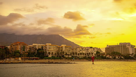 Golden-sunset-over-Malaga-coastline-with-calm-sea-and-cloudy-sky,-timelapse