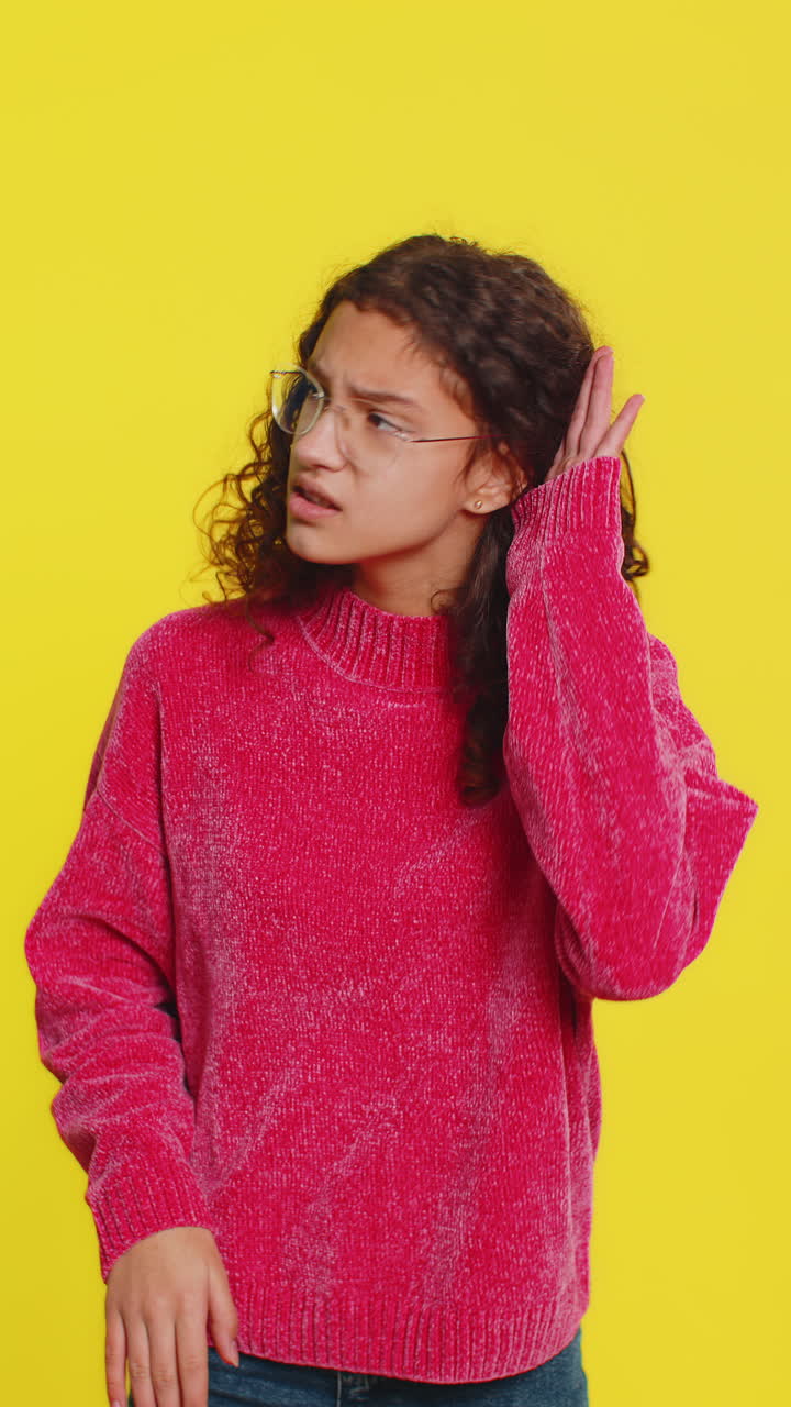 Teenager girl trying hear you looking confused and frowning keeping arm near ear for louder voice