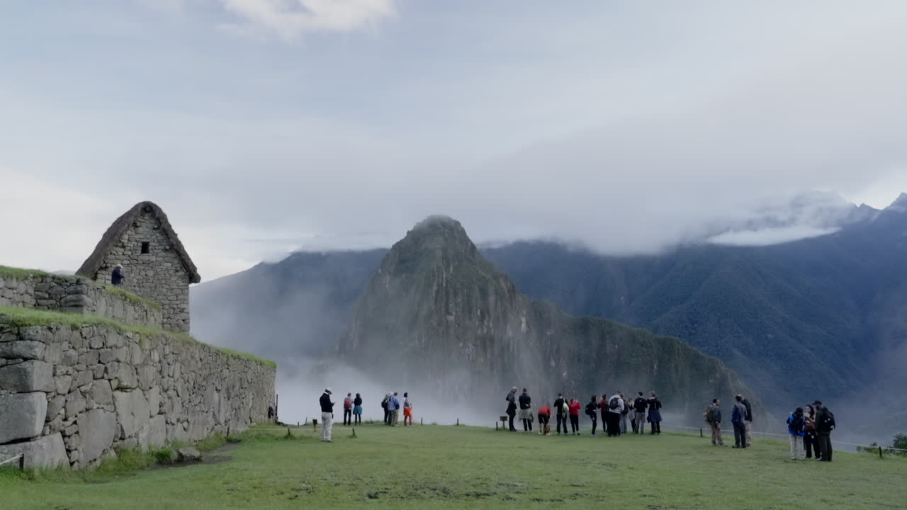 Tourists visit Machu Picchu lost city in foggy morning sunrise. Tourism Huayna Picchu in background