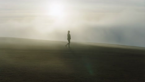 silhouette of a person walking in the fog on a sand dune