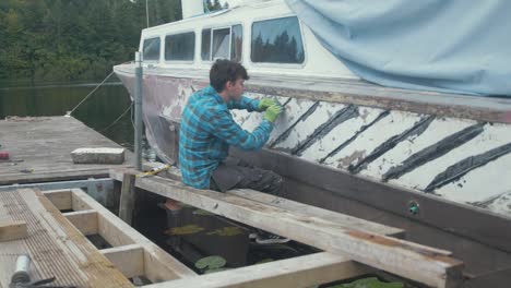 un joven carpintero sellando las costuras de la tabla del barco en el crucero de motor