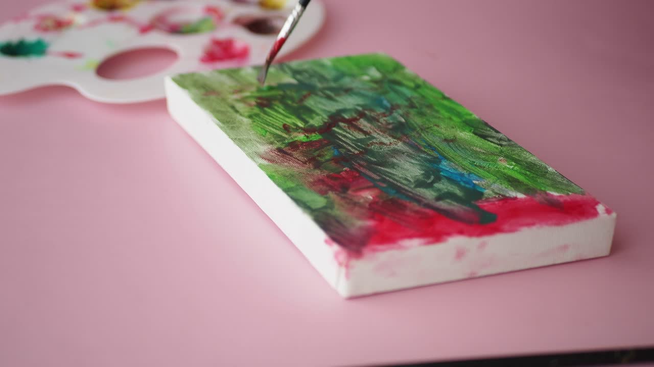 Primo piano di una mano che dipinge arte astratta su tela