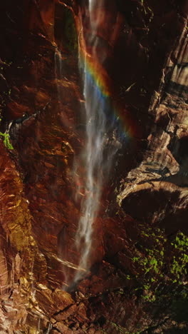 Little stream in the mountains of Yosemite, California, USA. Thin creek falling from cliffs creating rainbow in the air. Vertical video