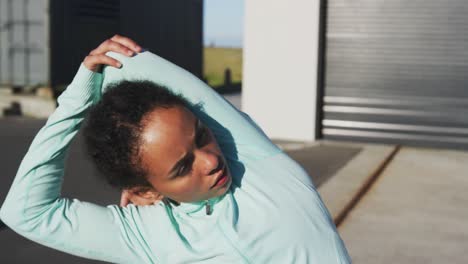 african american woman in sportswear stretching in street before exercising