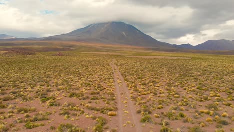 aerial cinematic shot following a dirt road showing lascar volcano in the atacama desert, chile, south america