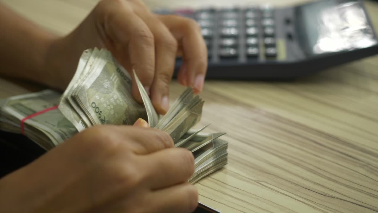 Closeup of hand counting 500 Indian rupee banknotes at a store