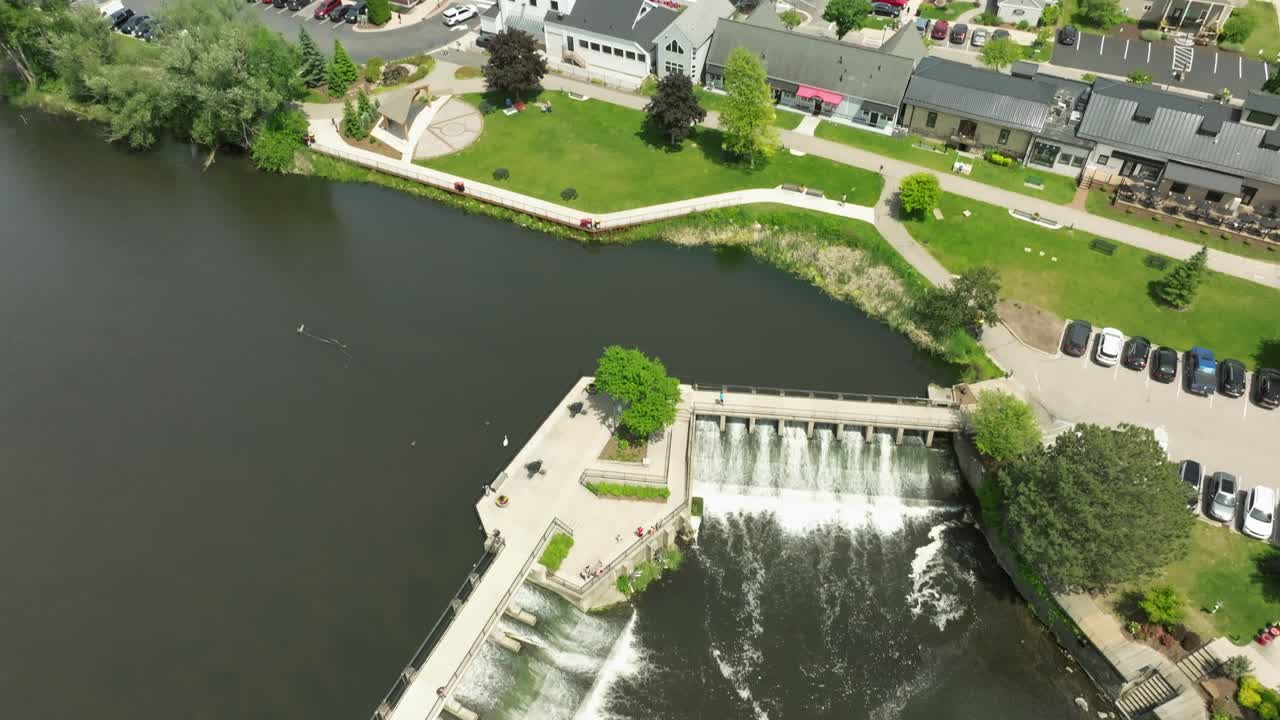Dam on Rogue River in Rockford, Michigan with drone video overhead and then tilting up to city