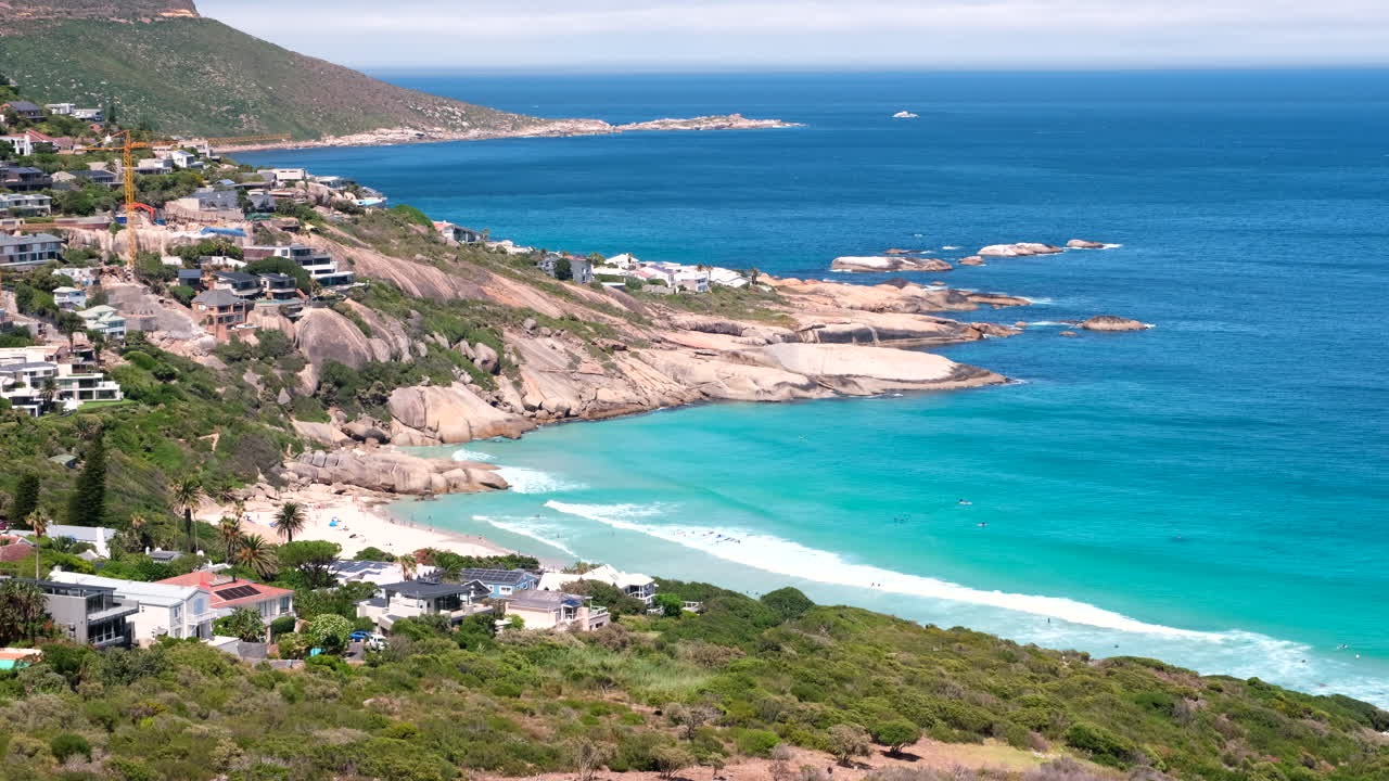 Sunset rocks boulders next to scenic Llandudno blue flag beach with surfers