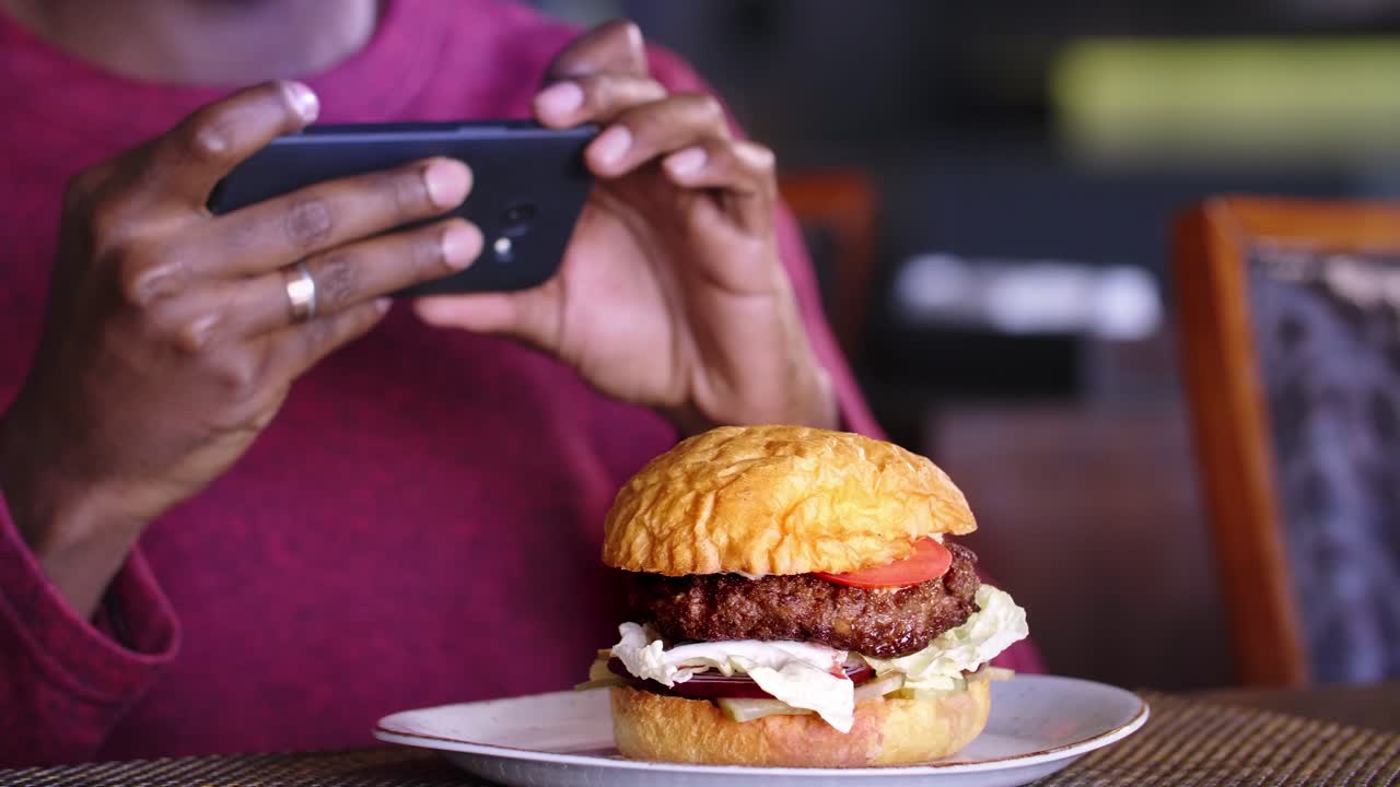 Person taking photo of a burger in a restaurant