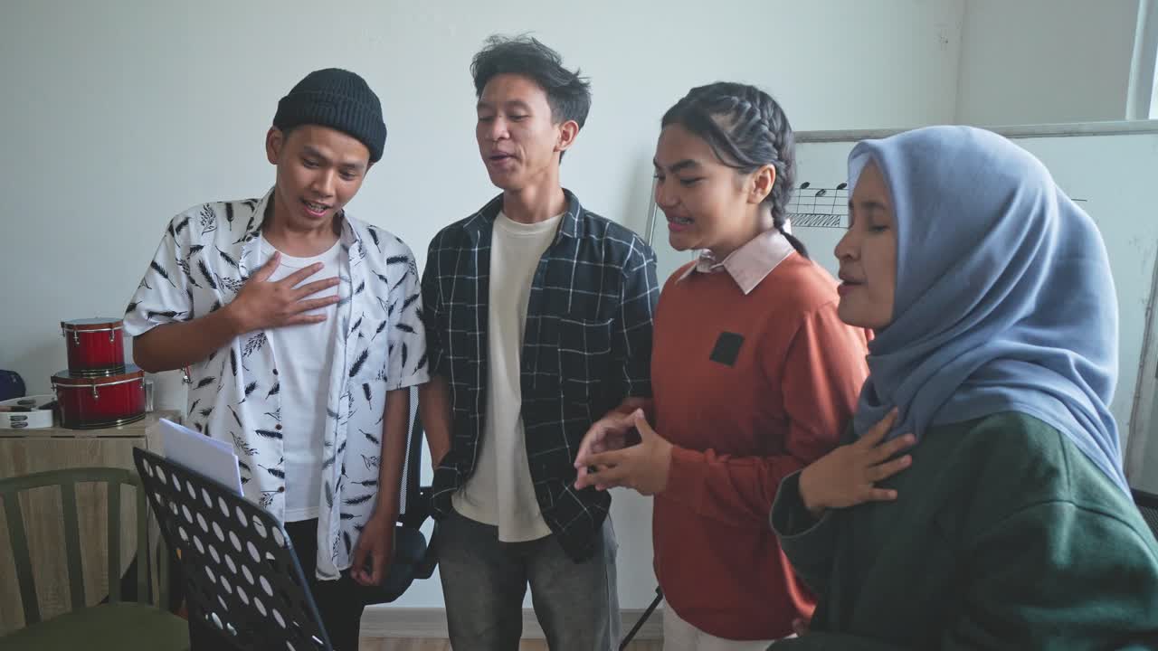 Asian Male And Female Students Practicing Singing In Choir At School